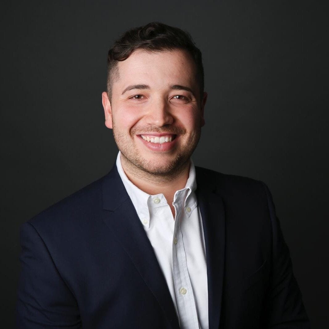 Portraitbild von Sammy Wardo Decandie, Geschäftsführer der VS Immobilienservice München GmbH. Er schaut direkt in die Kamera, hat weißes Hemd, einen dunkelblauen Anzug an, und vermittelt einen professionellen Eindruck.